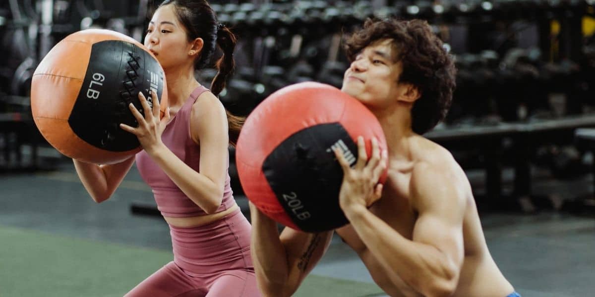 Couple using a ball weight for HIIT